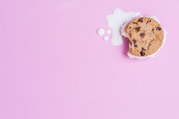 Melted ice cream and cookie on pink copy space background