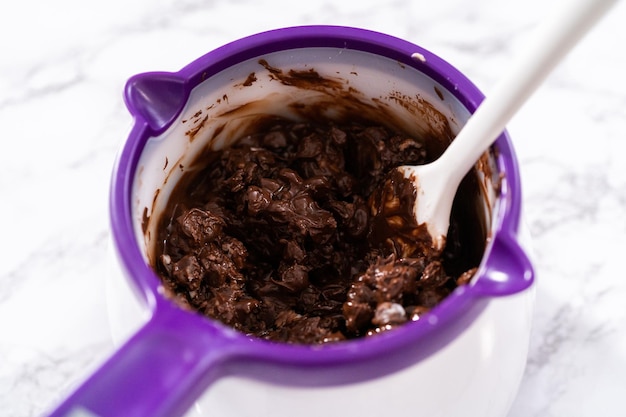 キャンディーの溶ける鍋でチョコレートチップを溶かして、チョコレートで覆われたイチゴを作ります。