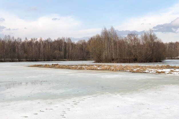 Foto ghiaccio che si scioglie sulla superficie del lago ghiacciato nel paesaggio forestale di inizio primavera