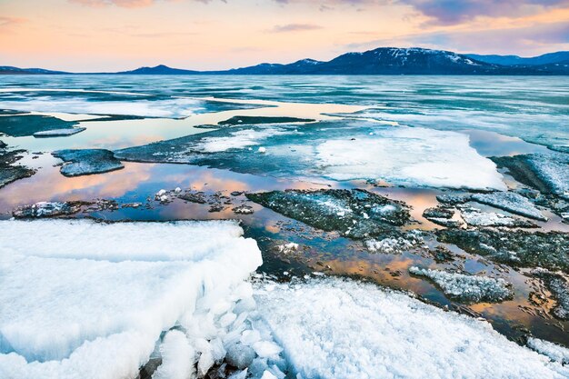 Melting ice on the lake at sunset. Beautiful spring landscape.