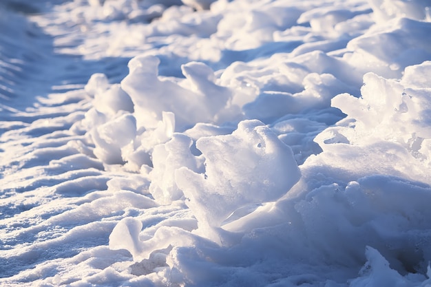 La neve e il ghiaccio che si sciolgono si chiudono alla luce del sole serale in inverno