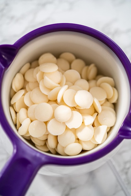 Melting white chocolate chips in a candy melting pot to bake peppermint white chocolate cookies.