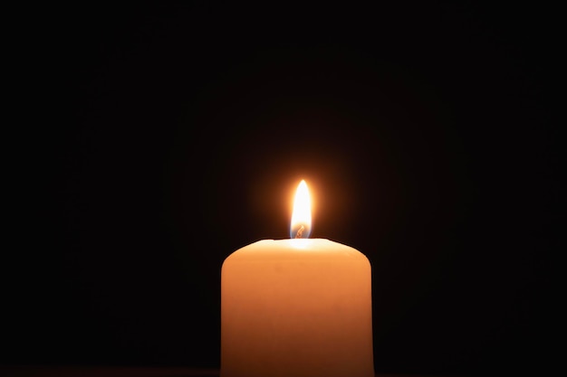 A memorial candle on a dark background Burning candle on black background copy space