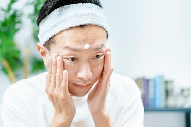 Men applying moisturizing cream to their face in the room