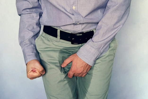 Men are scratching the penis against blue gray background. People itching crotch. Human body problem or healthcare and medicine concept. incontinence and wet pants