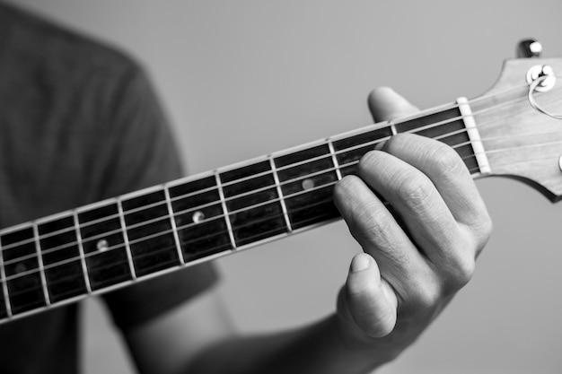 Men catch chords are learning to play guitar. Closeup musicians are catching guitar chords. Male musicians hold chords and strum guitar.