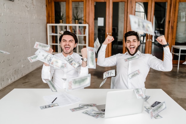 Мужчины зарабатывают много денег в офисе, доллары падают с неба