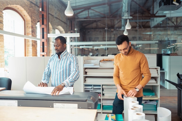 Men feeling busy. Two hard-working men feeling busy while working on book printing