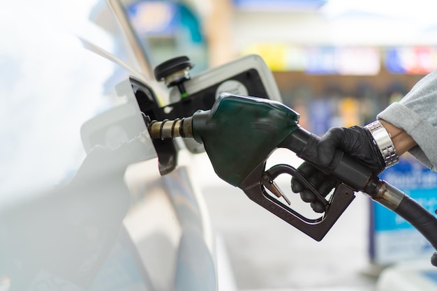 Men fills petrol into his car at a gas station