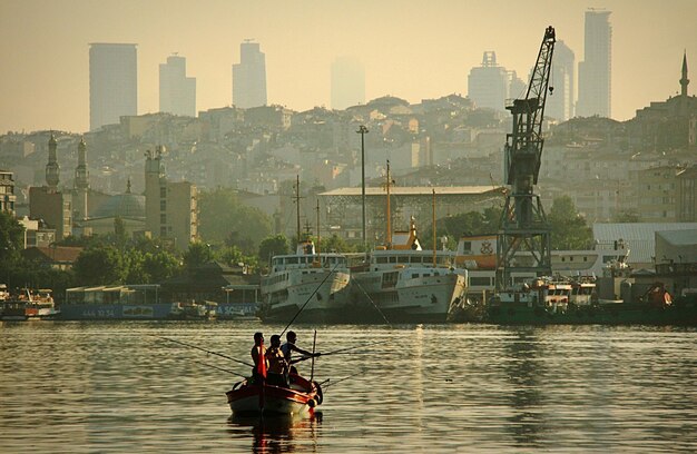Men fishing in bosphorus against city