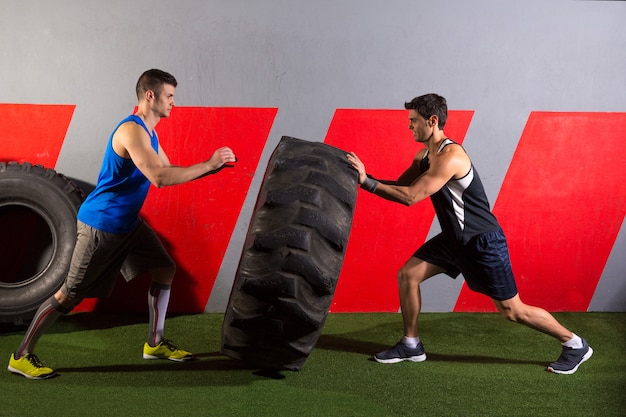 Gli uomini lanciando un esercizio di allenamento palestra di pneumatici trattore