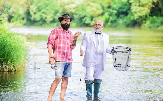 Men friends relaxing river background. Personal instructor. Bearded man elegant businessman fish together. Learn to fish. Fishing skills. Fish with companion who help in emergency. Expert fisherman.