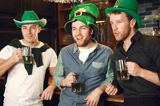 Foto uomini con cappelli verdi. gli amici celebrano il giorno di san patrizio. celebrazione in un pub.