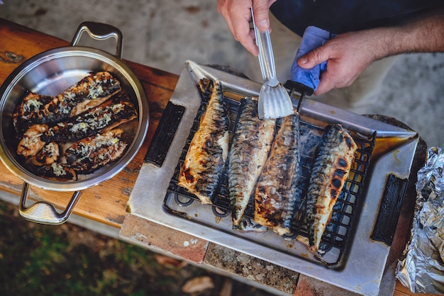 Men grilling fish on electric barbecue