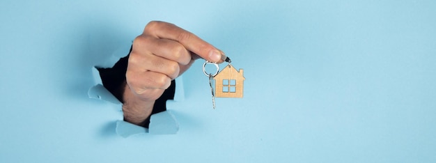 Men hand holding key with house shaped keychain