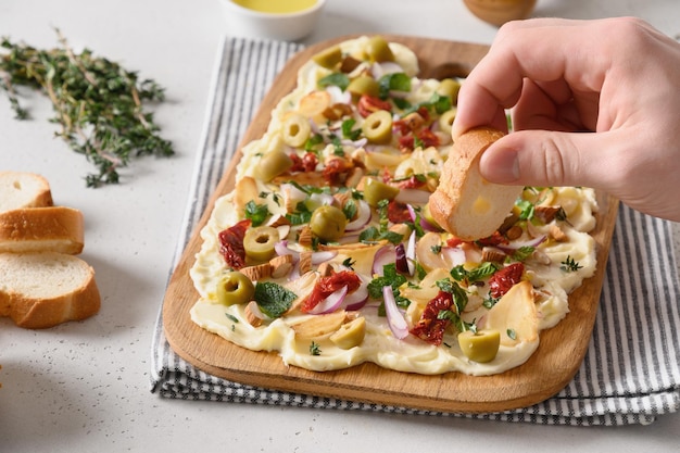 Men hand spreads bread with cheese from butter board Close up