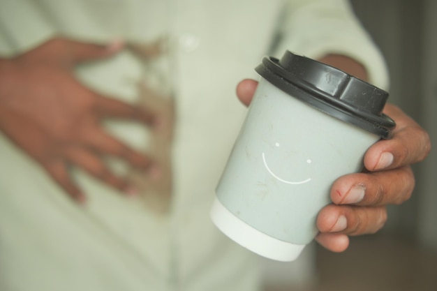 シャツの上にコーヒーをこぼした男性の手