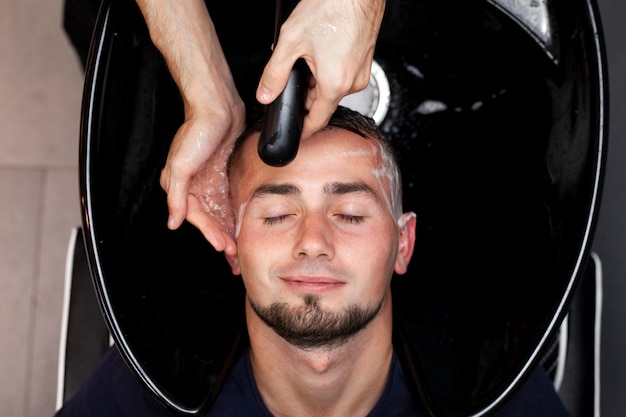 男性は理髪店で髪を洗っています