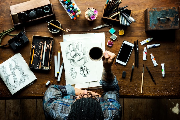 Men hipster holding coffee and artwork on the table