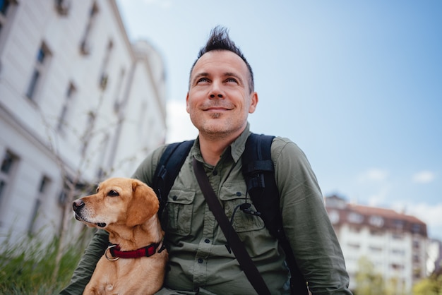 Photo men and his dog sitting on the city street