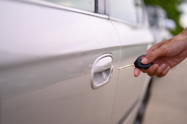 Men hold the car keys to open the car.