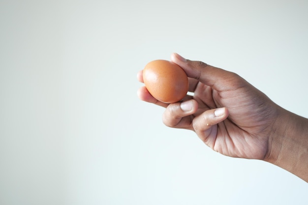 Men holding a egg against white wall