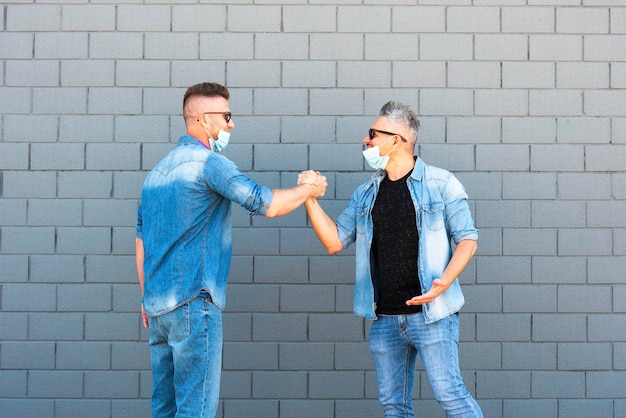 Photo men holding hands while standing against wall