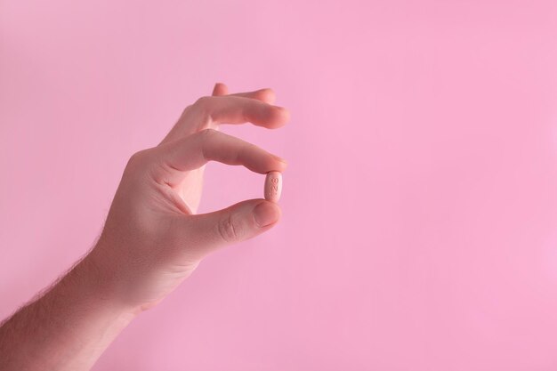 Men holding hiv therapy pills on pink background