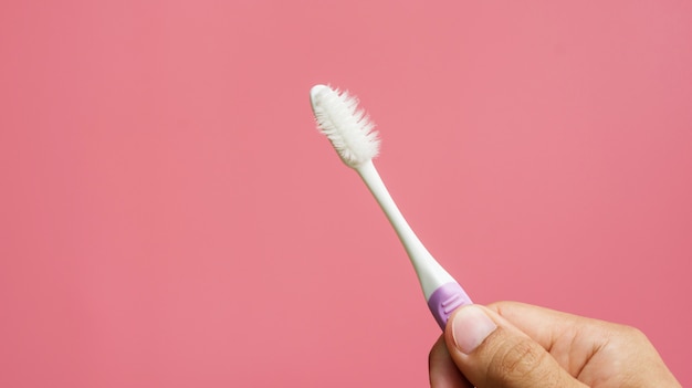 Men holding old toothbrush on a pink background.