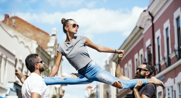 Men holding pretty girl leg split on shoulders