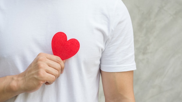 Men holding a red fabric heart on a gray background.