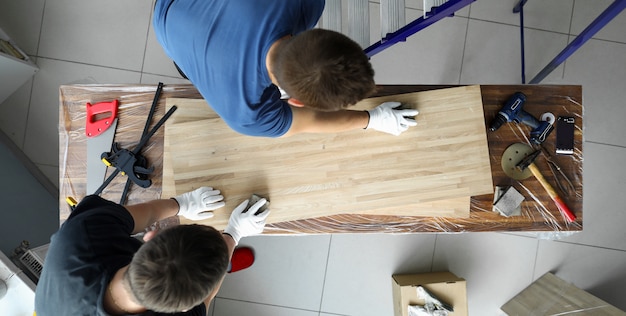 Men joiners polish wooden surface canvas on table. Installation on surface workbench various tools for processing workpieces. Special carpentry tools and suitably equipped workplace