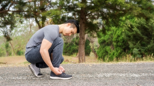 Men knelt down to do up his shoelaces prepare exercise.