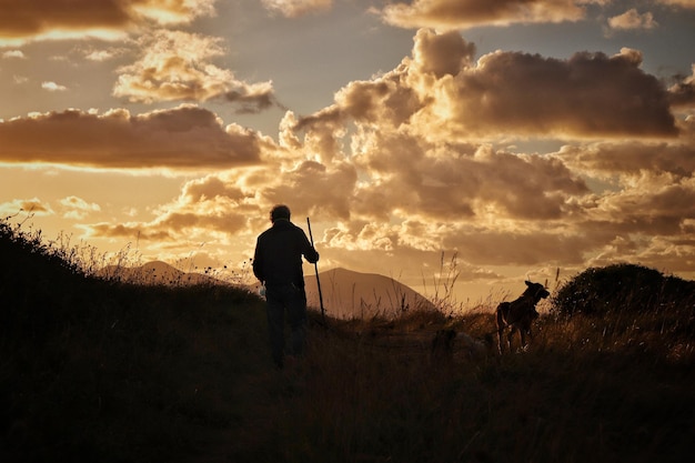Фото Мужчины на поле против неба во время захода солнца