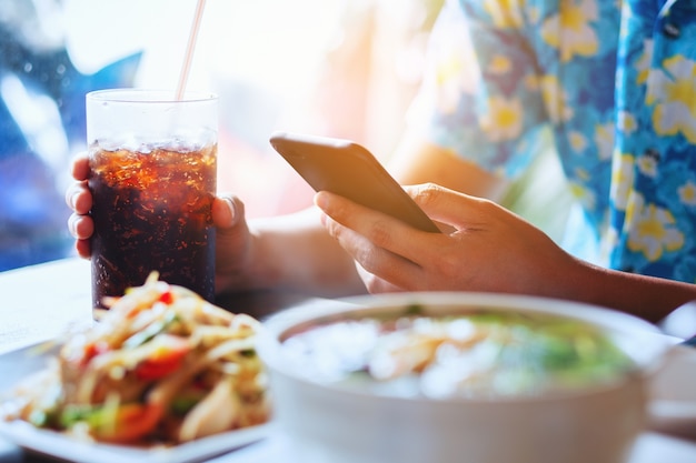 Photo men play smartphone and hand hold of glass soft drink in cafe restaurant wait food