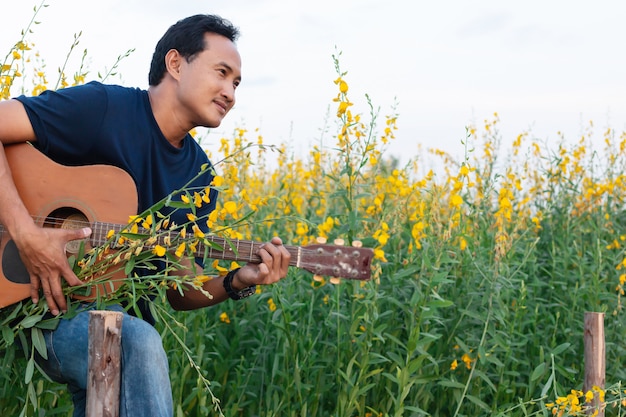 Men playing guitar in Beautiful Sunhemp flower in garden