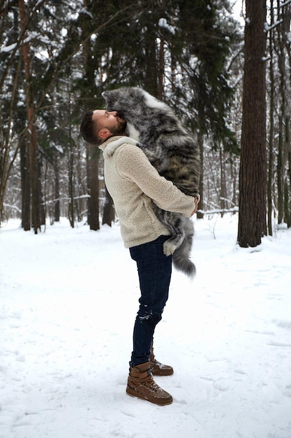 Men playing with siberian husky in winter forest and park animals and ecology Pet lover Dog human s friend concept