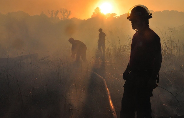 men in protective workwear standing on field during sunset