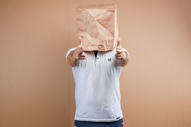 Men put a paper bag over their heads, shoots their fingers at you Isolate on yellow background, images are easy to crop for use anywhere, copy space.