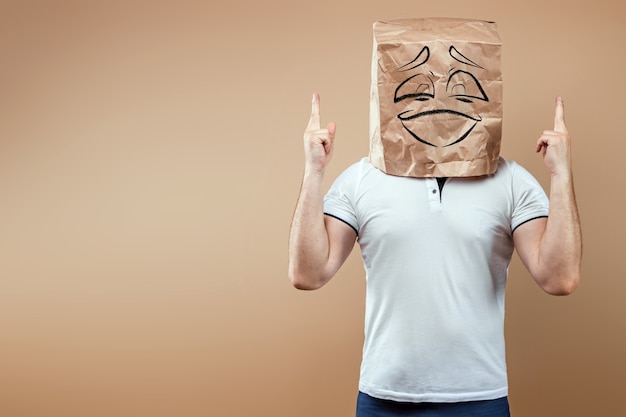 Men put a paper bag on their heads with a smiling face and show thumbs up. Isolate on yellow background, images are easy to crop for use anywhere, copy space