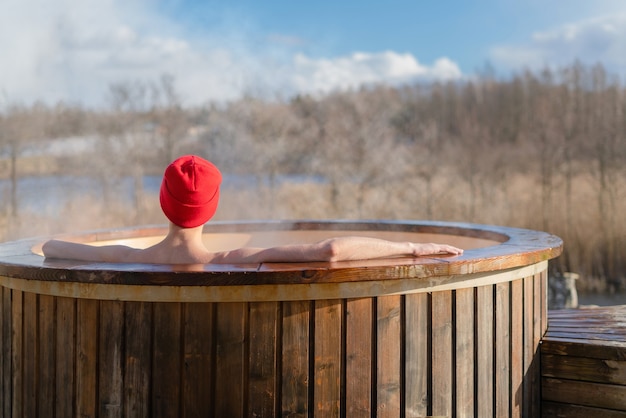 Men relaxing in wooden hot tub outside.