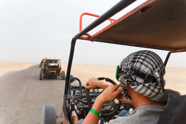 Uomini in sella a una carrozzina nel deserto