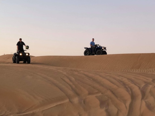 Photo men riding quadbike on desert