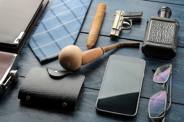 Accessori da uomo. stile maschile. smartphone, porta biglietti da visita, profumo, pipa, borsa su fondo di legno blu.