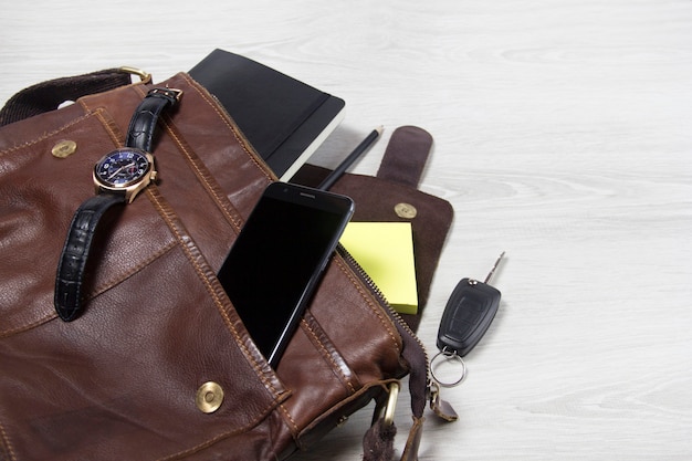 Men's accessories with brown leather bags, belt and sunglasses on wooden table over wall background