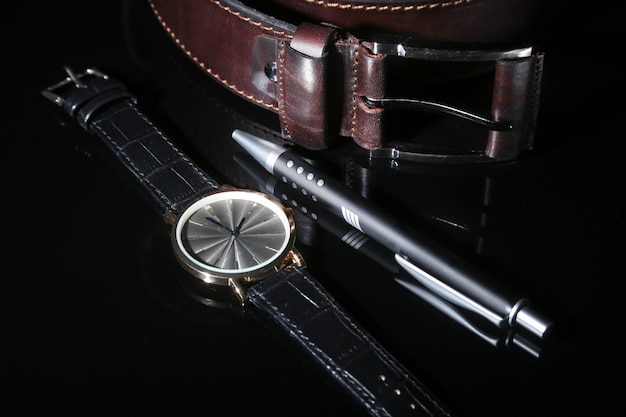 Men's accessories with brown leather wallet, belt and watch.