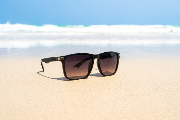 Men's black Sunglasses on the beach. Beautiful sea view wallpaper, background