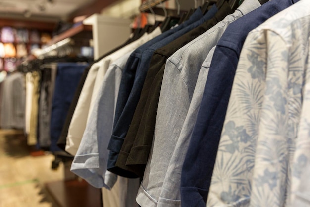 Men's casual shirts on hangers on a rail in a store Summer collection of cotton and linen products Side view Closeup Selective focus