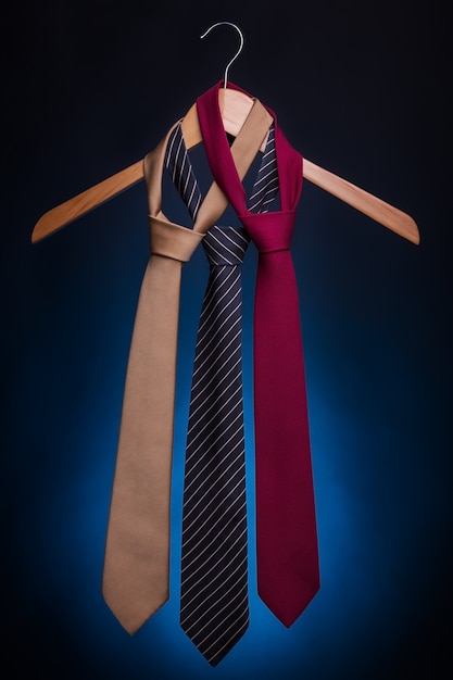 Men's fashionable ties on a hanger. On a blue background.