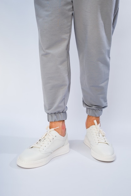 Men's feet in white everyday sneakers made of natural leather on lacing.